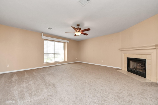 unfurnished living room with carpet floors, visible vents, ceiling fan, a tile fireplace, and baseboards