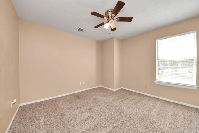 spare room featuring carpet, visible vents, ceiling fan, and baseboards