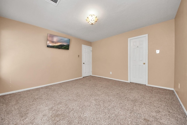 spare room with carpet floors, visible vents, and baseboards