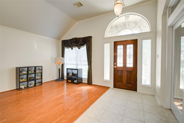 entrance foyer featuring lofted ceiling, visible vents, light wood-style flooring, ornamental molding, and baseboards