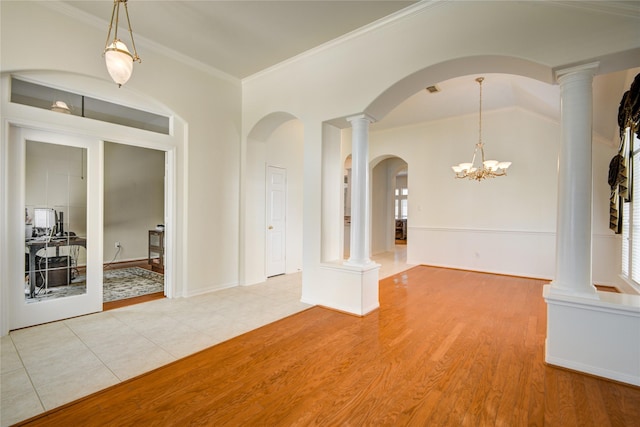 unfurnished dining area featuring decorative columns, baseboards, vaulted ceiling, crown molding, and light wood-style floors