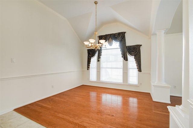 unfurnished dining area with a notable chandelier, decorative columns, vaulted ceiling, wood finished floors, and baseboards