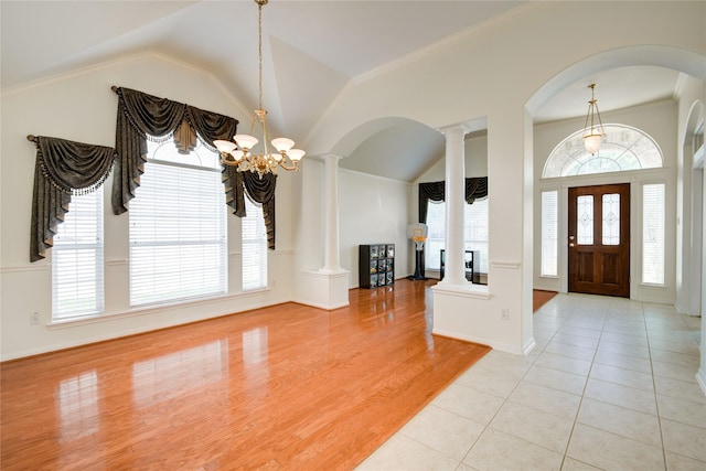 entrance foyer with baseboards, wood finished floors, crown molding, ornate columns, and a notable chandelier