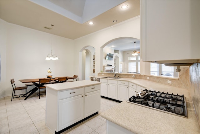 kitchen with light tile patterned floors, arched walkways, stainless steel gas cooktop, a kitchen island, and a sink