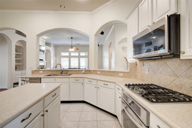 kitchen with crown molding, light tile patterned floors, stainless steel appliances, light countertops, and a sink