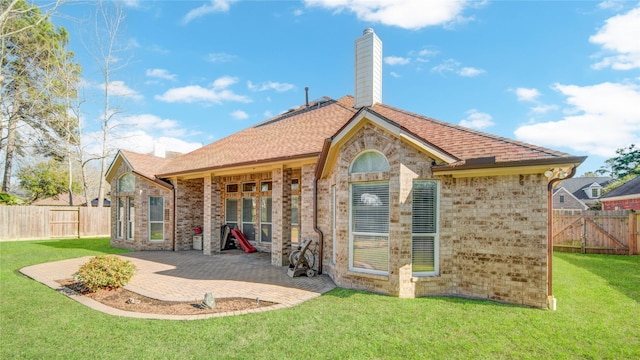 rear view of house featuring a patio area, brick siding, a chimney, and a lawn