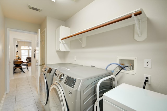 laundry room featuring arched walkways, light tile patterned floors, visible vents, independent washer and dryer, and cabinet space