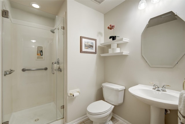 bathroom featuring toilet, a sink, a shower stall, tile patterned flooring, and baseboards