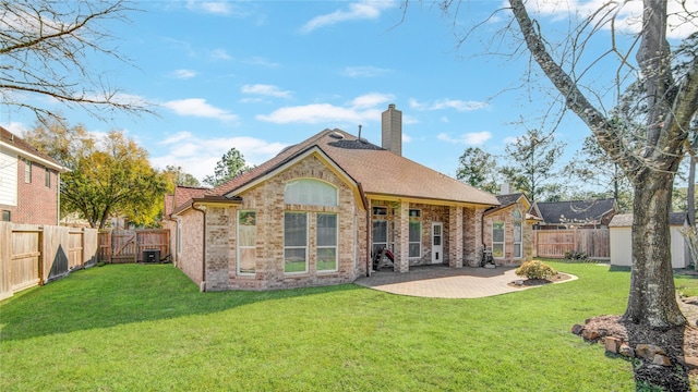 back of property featuring a fenced backyard, a chimney, and brick siding