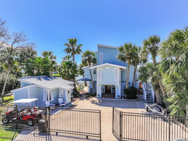 view of front of house featuring a fenced front yard, stairway, and concrete driveway