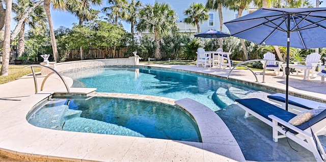 view of pool with a patio area, a pool with connected hot tub, and fence