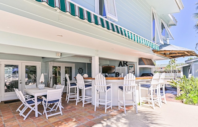 view of patio with outdoor dry bar, french doors, and outdoor dining space