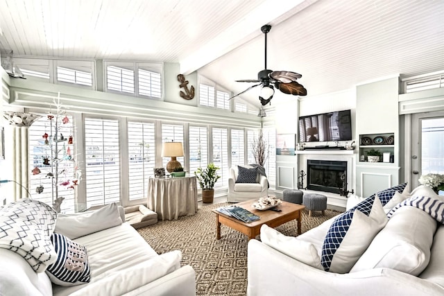 living room with lofted ceiling with beams, a fireplace with raised hearth, and a ceiling fan