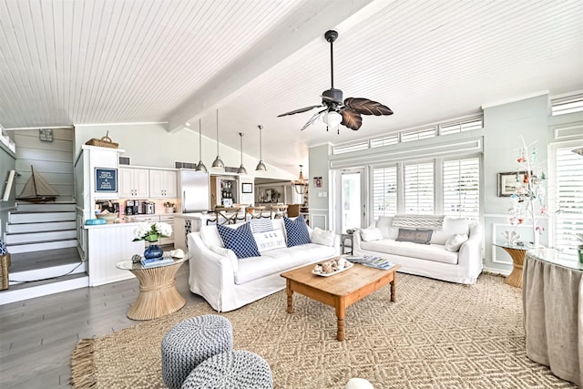 living area with a ceiling fan, lofted ceiling with beams, a wainscoted wall, stairs, and light wood-type flooring