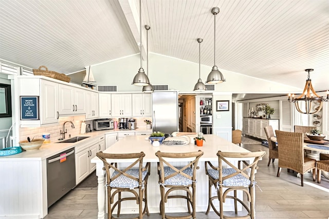 kitchen featuring stainless steel appliances, a sink, white cabinetry, a kitchen breakfast bar, and light countertops