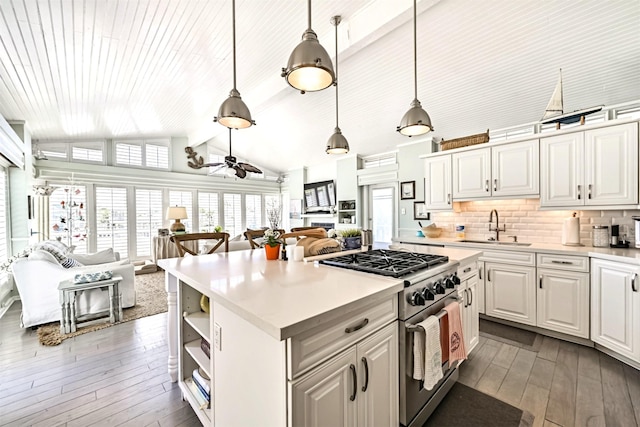 kitchen featuring light countertops, lofted ceiling with beams, a sink, high end range, and hardwood / wood-style floors