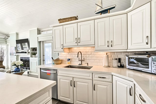 kitchen with white cabinets, stainless steel dishwasher, light countertops, and a sink