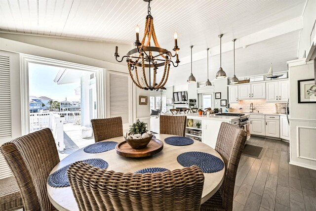 dining area featuring lofted ceiling, dark wood-style flooring, and an inviting chandelier