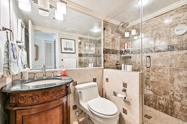 full bathroom with crown molding, tile walls, a textured ceiling, a shower stall, and vanity