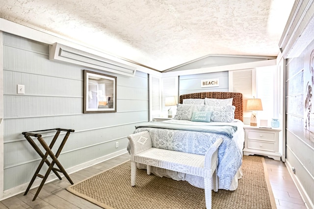 bedroom featuring vaulted ceiling, a textured ceiling, and wood finished floors