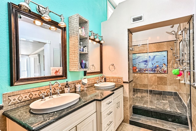 bathroom featuring visible vents, a sink, a shower stall, and double vanity