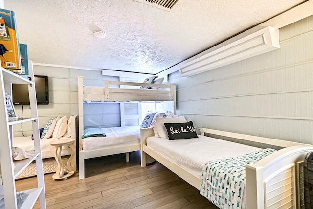 bedroom with visible vents, a textured ceiling, and wood finished floors