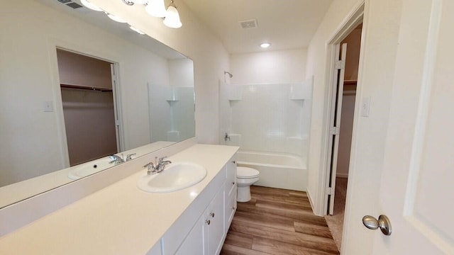 bathroom featuring a walk in closet, visible vents, toilet, vanity, and wood finished floors