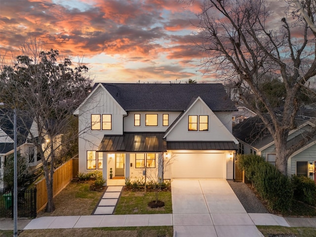 modern farmhouse style home with a shingled roof, concrete driveway, a standing seam roof, fence, and board and batten siding