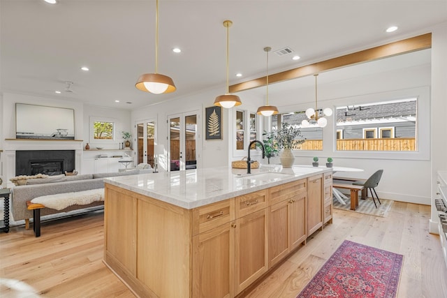 203 Munford St, Houston, TX 77008 - kitchen with light brown cabinets, light stone counters, visible vents, a sink, and a kitchen island with sink