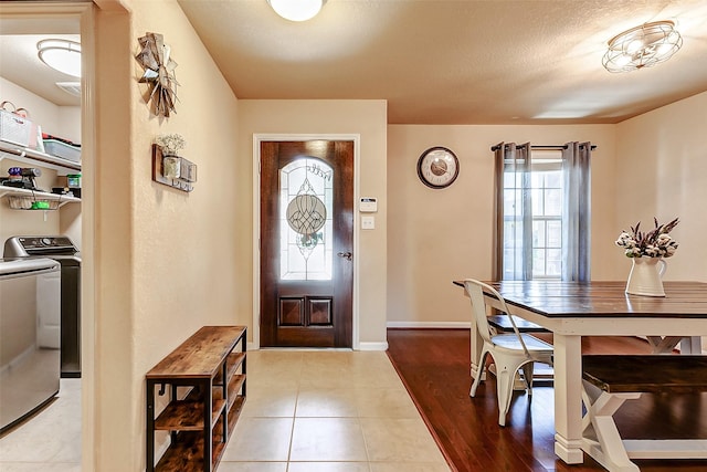 foyer featuring a textured ceiling, baseboards, separate washer and dryer, and tile patterned flooring