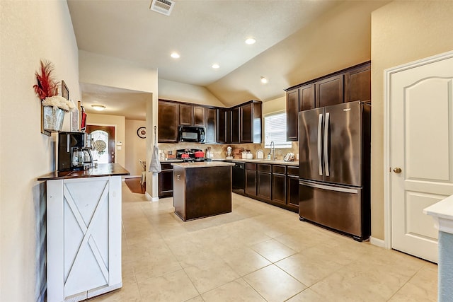 kitchen featuring visible vents, freestanding refrigerator, dark brown cabinets, black microwave, and tasteful backsplash