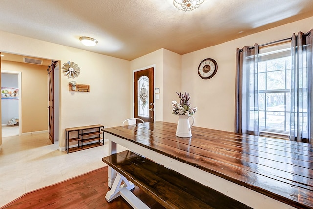 tiled dining room with visible vents and a textured ceiling