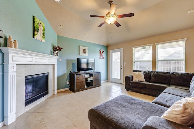 living area with ceiling fan, baseboards, lofted ceiling, light tile patterned floors, and a tile fireplace