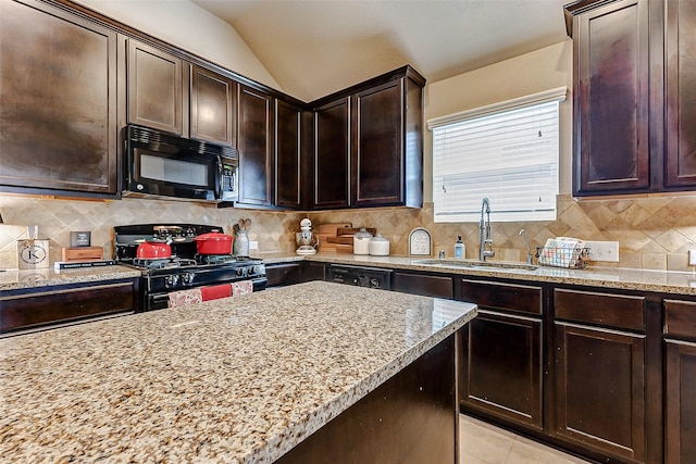 kitchen featuring light stone counters, lofted ceiling, a sink, black appliances, and backsplash