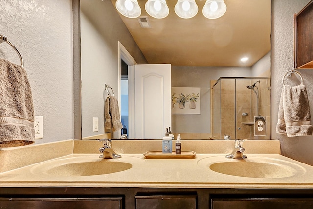 full bathroom featuring double vanity, visible vents, a stall shower, and a sink