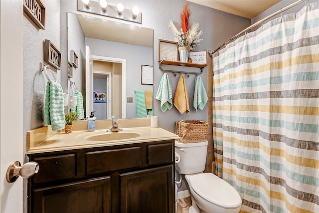 full bath with vanity, a shower with shower curtain, toilet, and a textured wall