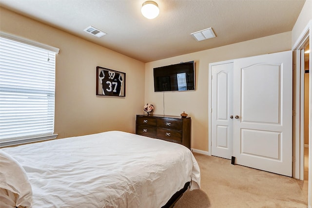 bedroom featuring baseboards, visible vents, and light carpet