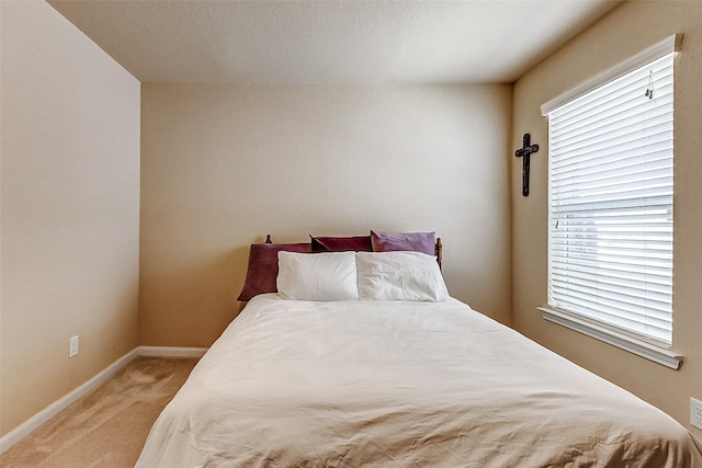 bedroom featuring light colored carpet and baseboards