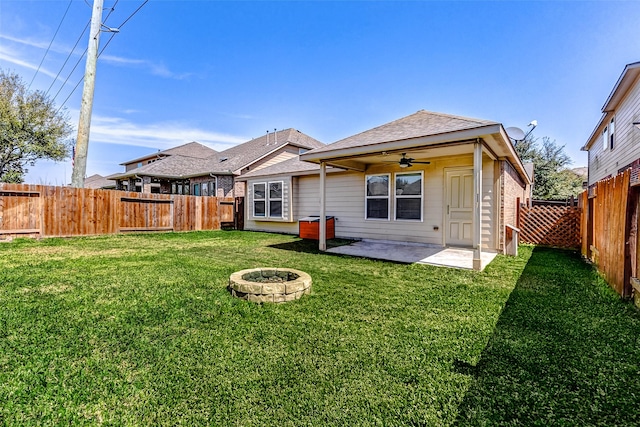 back of property with a fire pit, a yard, a fenced backyard, a ceiling fan, and a patio