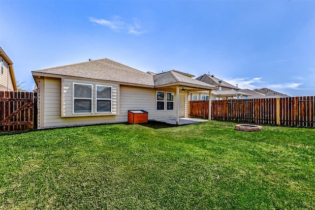 back of property featuring a lawn, a ceiling fan, a fenced backyard, a shingled roof, and a patio area