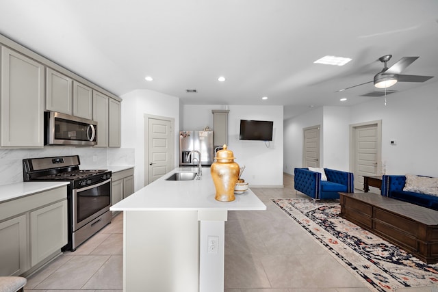 kitchen featuring stainless steel appliances, gray cabinets, a sink, and decorative backsplash