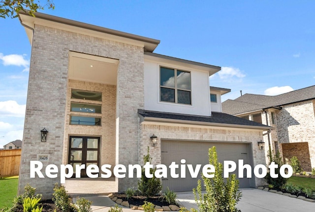 view of front of property with driveway, brick siding, an attached garage, and fence