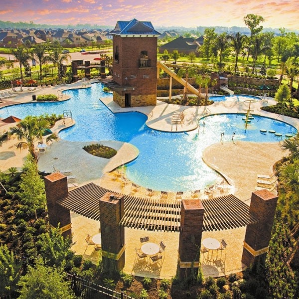 pool at dusk with a patio, a fireplace, and a community pool