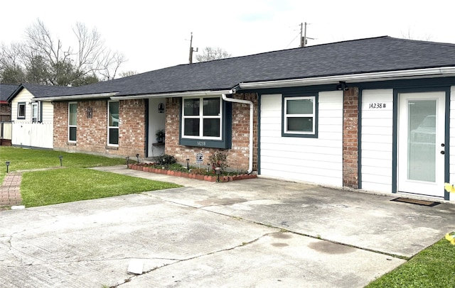 ranch-style home featuring roof with shingles, brick siding, and a front lawn