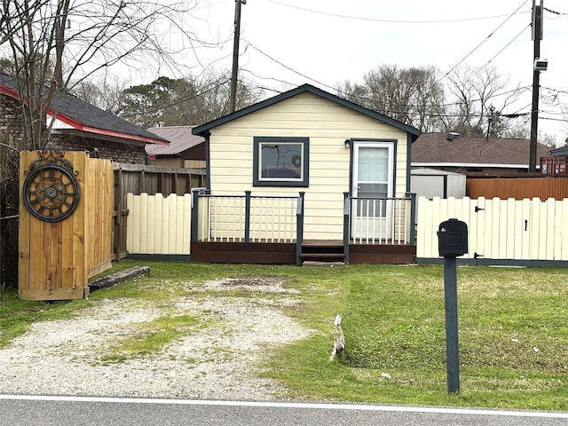 exterior space with driveway, fence, an outbuilding, and a front yard