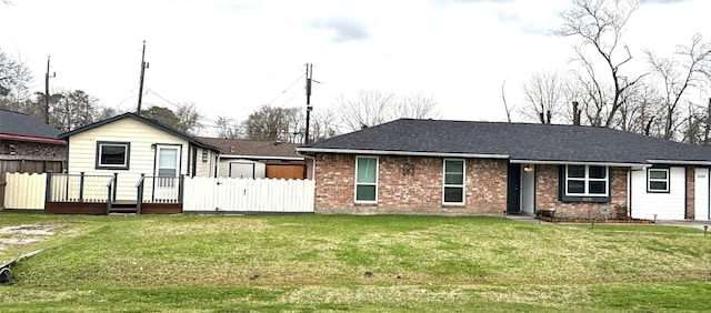 ranch-style house featuring a front lawn, fence, and brick siding