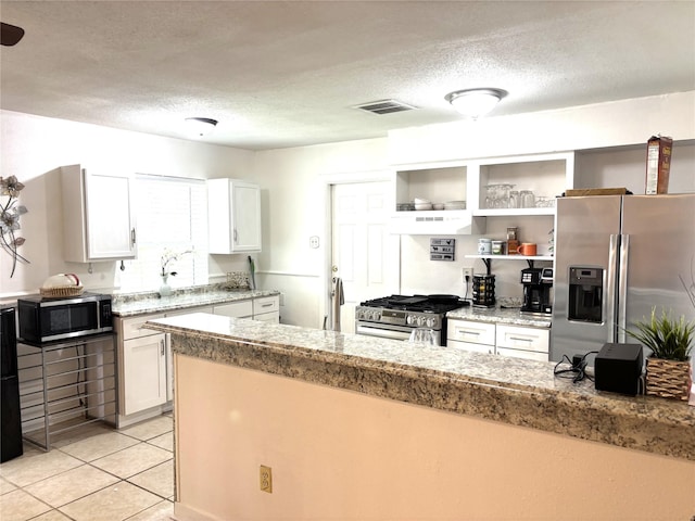 kitchen featuring light tile patterned floors, a textured ceiling, stainless steel appliances, visible vents, and white cabinets