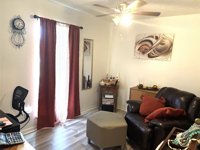 living room with baseboards, a ceiling fan, and wood finished floors