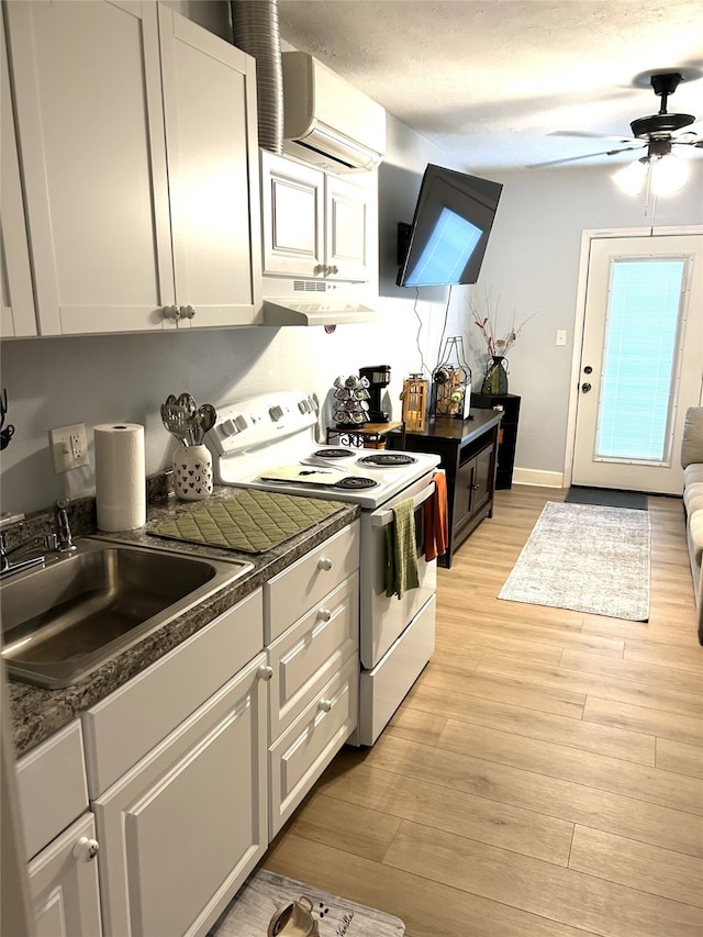 kitchen with a wall unit AC, light wood-style flooring, under cabinet range hood, a sink, and white range with electric stovetop