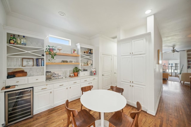 dining area featuring ceiling fan, recessed lighting, beverage cooler, wood finished floors, and ornamental molding